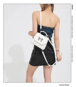 Detailed back view of a white leather crossbody bag with silver bow accent on model