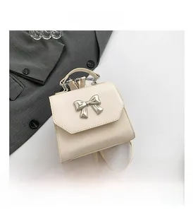 Detail of cream mini backpack with silver metal bow and premium stitching craft