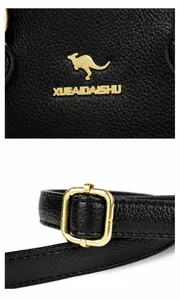 Détails du logo kangourou doré et boucle en métal sur un sac en cuir litchi noir