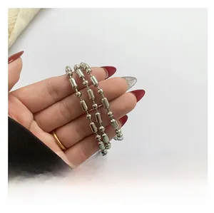 Close-up of a silver metal chain strap with beads and a large pearl on a handbag