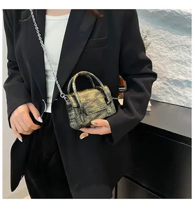Detail of a dark gothic crossbody bag with skull motif and metal chain strap on a black blazer