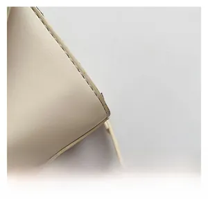 Close-up of fine stitching and smooth leather texture on an off-white shoulder bag