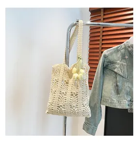 Detail of hollow crochet straw tote bag with a yellow tulip charm and woven texture