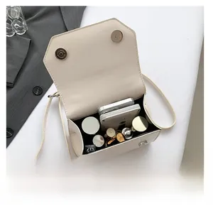 Detail view of the interior capacity of a cream white flap bag showing phone and lipstick