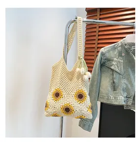 Detail of beige knit tote bag with sunflower motif and tulip charm on casual display