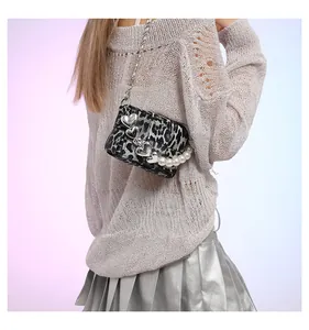 Close-up of leopard print crossbody bag with heart pendant and pearl chain detail
