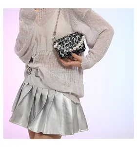 Detail of leopard print mini crossbody bag with heart chain and pearl handle accessory