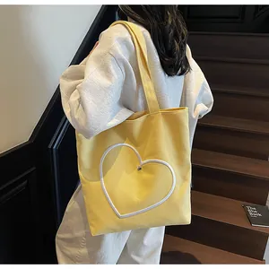 Close-up of the large white heart patch and metal button detail on yellow canvas tote bag