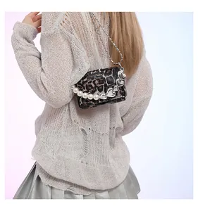 Detail of leopard print crossbody bag featuring large pearls and heart metal charm