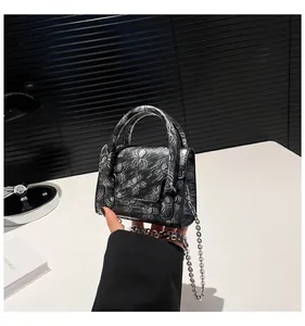 Detail of gothic spider embossed crossbody bag with metallic chain and curved handle