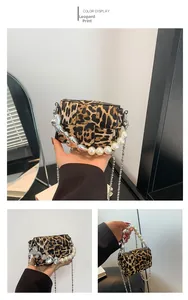 Detail of yellow leopard print crossbody bag with pearl handle and silver heart chain