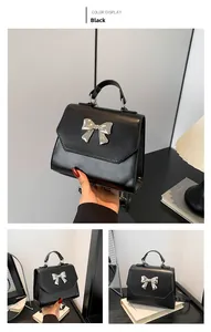 Detail view of black PU leather handbag featuring a stylish silver bow and top handle