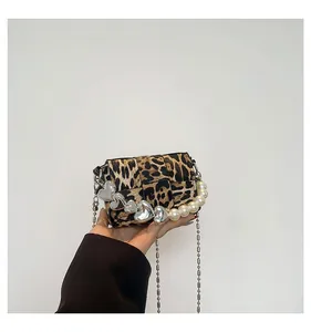 Detail of leopard print crossbody bag with pearl heart handle and metal chain