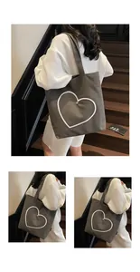 Detail of grey canvas tote bag with white embroidered heart and metal rivet accents