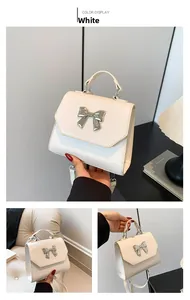 Detail of white leather handbag with silver butterfly clasp and long crossbody strap