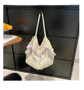 Detail of knit shoulder bag featuring purple ruffle trim and a tulip flower pendant