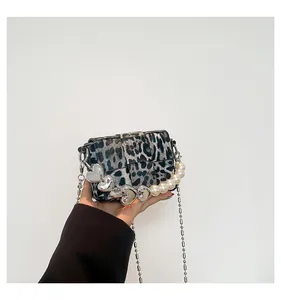 Close-up of leopard print crossbody bag with silver heart charms and pearl chain detail