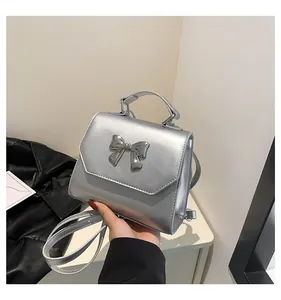 Detailed view of metallic silver handbag featuring a shiny bow and textured PU leather