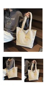 Detail of white canvas tote bag featuring yellow heart embroidery and sturdy handles