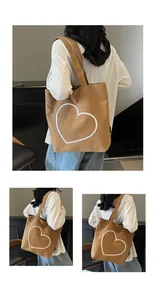 Detail of a brown canvas tote bag featuring embroidered heart outline and dual straps