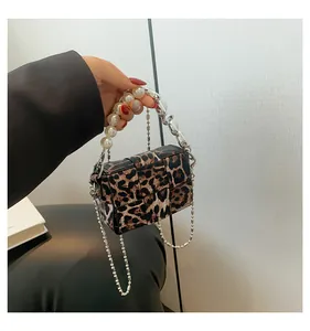 Detail view of leopard print crossbody bag with large pearl handle and metal chain strap