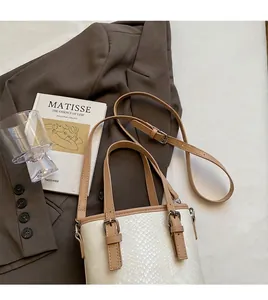 Detail des verstellbaren braunen Schultergurts an einer weißen Eimertasche mit Schlangenmuster