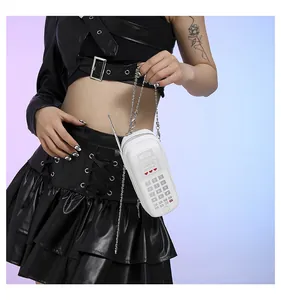 Détail d'un sac à bandoulière blanc en forme de téléphone vintage avec chaîne argentée