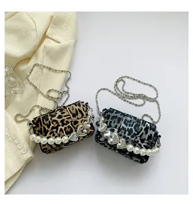 Detail of leopard print flap bags with heart metal and pearl handle on white background