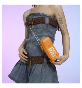 Détail du sac bandoulière orange en forme de téléphone rétro avec clavier et bandoulière chaîne