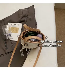 Details zur geräumigen Innenkapazität der beigen Beuteltasche mit Perlenanhänger