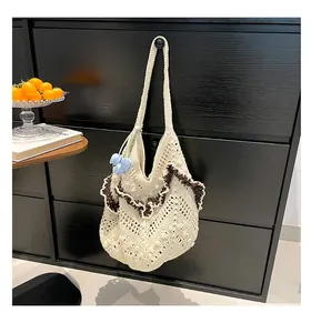 Close-up of cream crochet shoulder bag with brown ruffle edges and floral charm