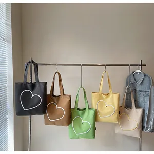 Detailed row of various colored canvas tote bags with heart embroidery on metal hangers