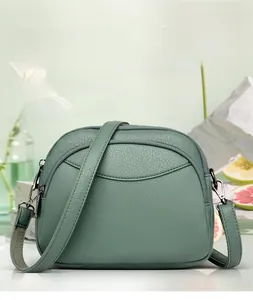 Green leather crossbody bag detail featuring three zipper layers and silver metal hardware