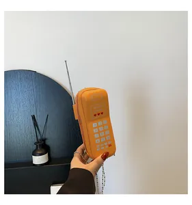 Détail du sac bandoulière orange créatif en forme de téléphone rétro avec chaîne en métal