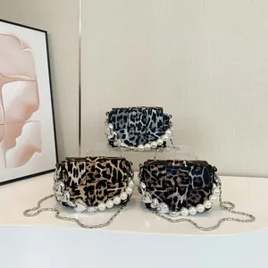 Three leopard print crossbody bags with pearl handles and metal heart charms on display