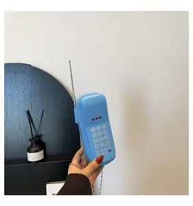 Détail du sac à bandoulière bleu en forme de téléphone rétro avec antenne créative