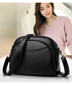 Detail of black pebbled PU leather bag with triple zip compartments and adjustable strap