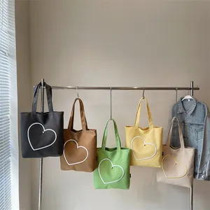 Canvas tote bags with heart embroidery in five colors hanging on a rack for daily commute