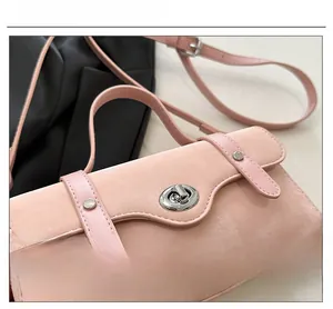 Close-up of pink suede handbag featuring a premium silver metal twist lock and straps