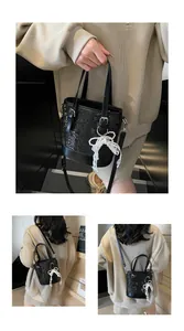 Detail der schwarzen Eimertasche mit Schlangenmuster, Spitzenbogen und Perlenanhänger