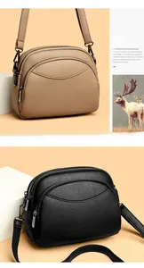 Detail of dual zipper compartments on textured leather crossbody bags in khaki and black