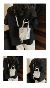 Detail der silbernen Beuteltasche mit Schlangentextur und weißem Spitzenbogen-Anhänger