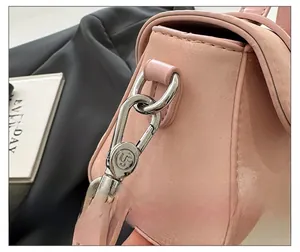 Detail of premium metal clasp on pink crossbody bag with engraved logo and leather texture