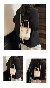 Detail der cremefarbenen Beuteltasche mit braunem Lederbesatz und Spitzen-Schleifen-Anhänger