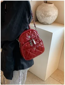 Λεπτομέρεια κόκκινου καπιτονέ mini σακιδίου από δέρμα PU με χρυσή αλυσίδα στο μοντέλο