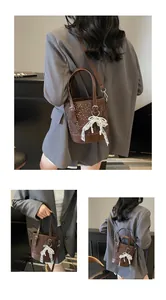 Detail einer dunkelbraunen Beuteltasche mit Webstruktur und weißem Spitzenbogen-Anhänger