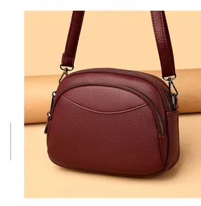 Detail view of burgundy PU leather crossbody bag with dual zippers and litchi texture