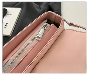 Close-up of the smooth silver zipper and round logo charm on a pink leather shoulder bag