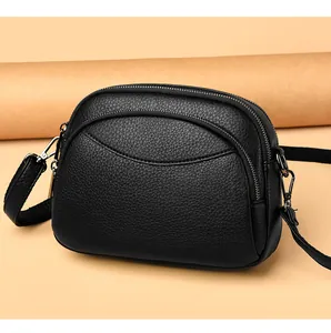 Close-up of black litchi pattern PU leather crossbody bag with three zipper compartments