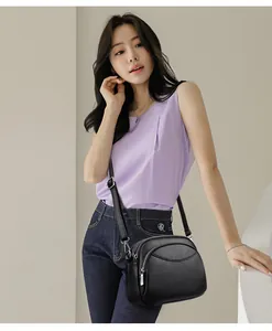 Detailed view of black pebbled PU leather crossbody bag with dual silver zippers on model